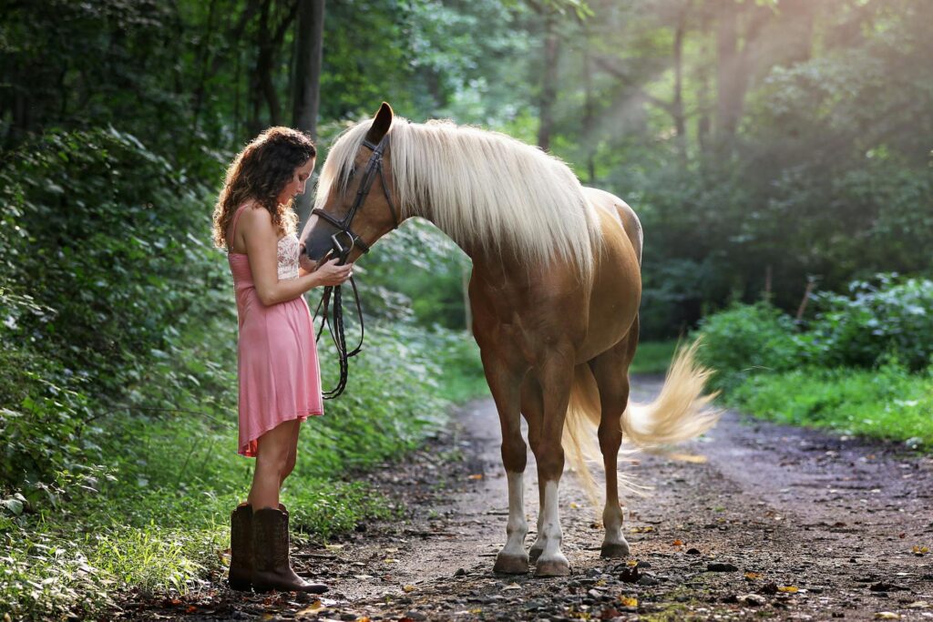 Mujer con un vestido rosado acariciando a un caballo en la cabeza